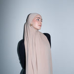 Woman wearing a beige hijab against a plain background